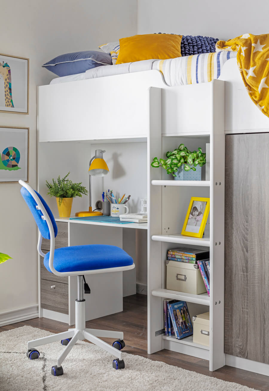 Dormitorio juvenil, de estilo moderno. Cama con escritorio incluido, de madera blanca y gris. Ropa de cama en colores blancos, amarillo y azul. Silla de escritorio de color azul, con ruedas. 