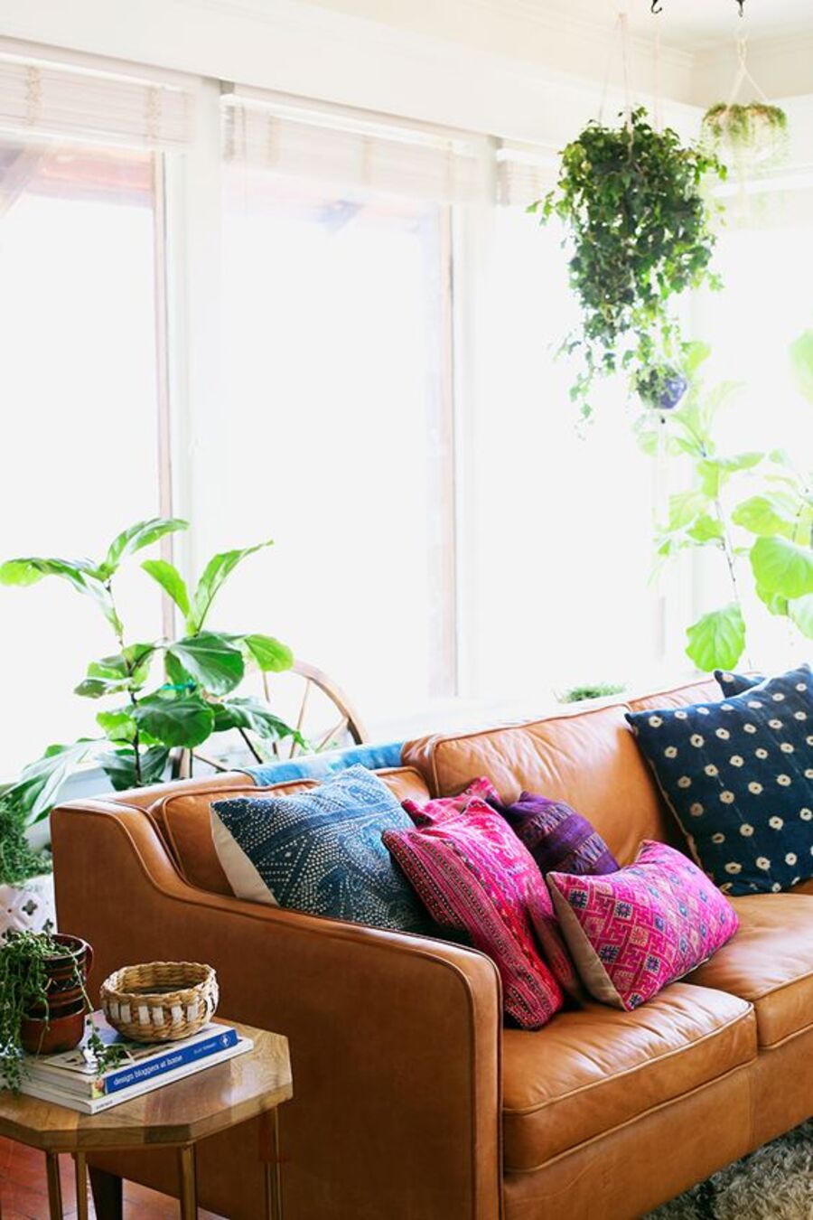 Living estilo boho, con futón café, con cojines fucsia, azul y morado estilo kilim. Mesa de apoyo lateral, de forma hexagonal, de madera.