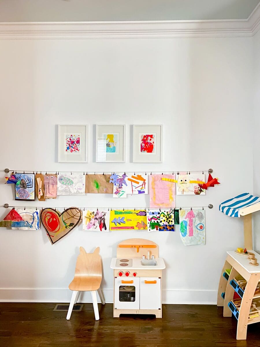Dormitorio Montessori con un muro galería conformado por arte infantil colgados en ganchos. 
