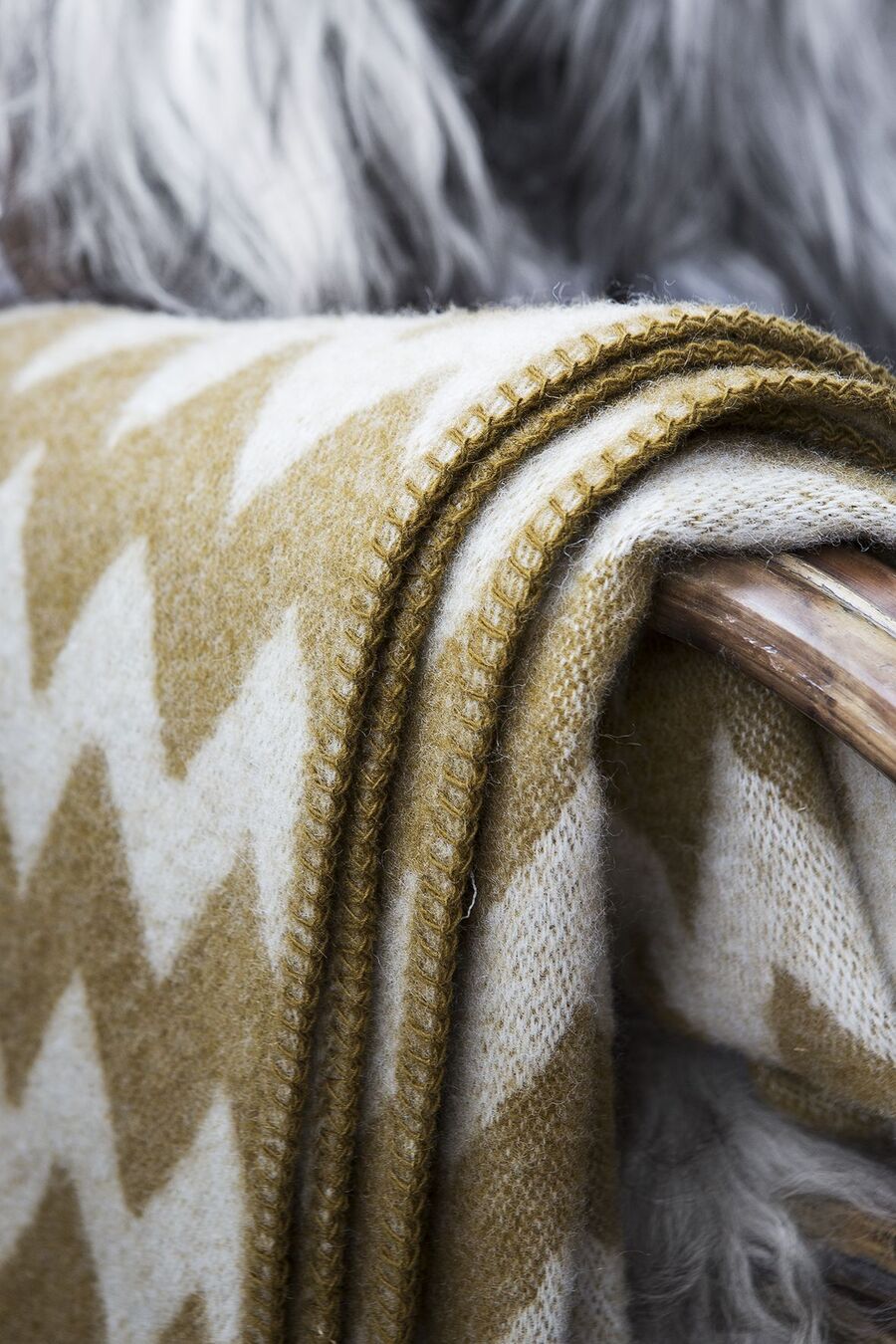 Detalle de una manta de lana, con diseño zig zag en color blanco y verde. 