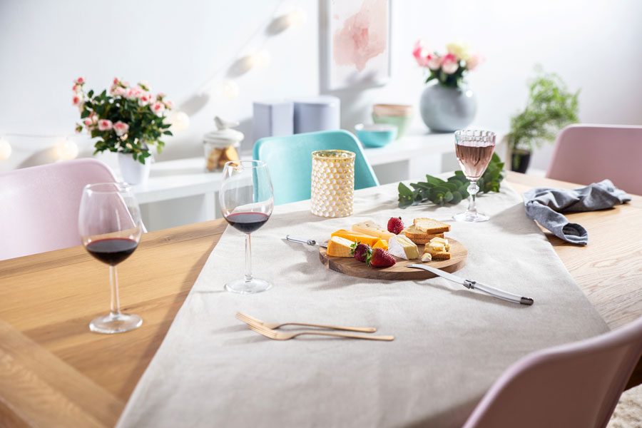 mesa de comedor con tabla de quesos para picar y dos copas de vino tinto