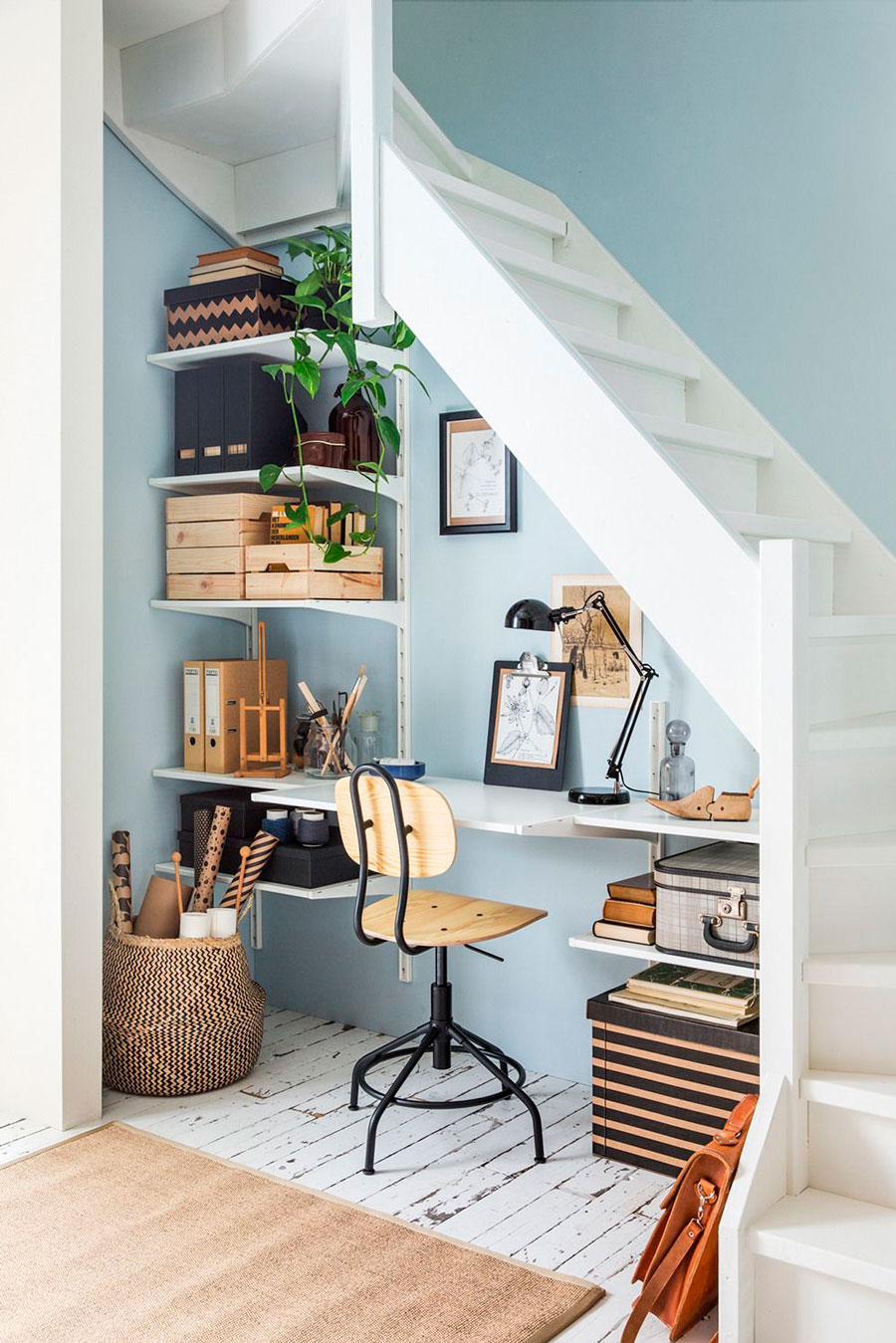 pequeño escritorio bajo una escalera, todo decorado con una paleta de colores blanco con crema, arena y madera